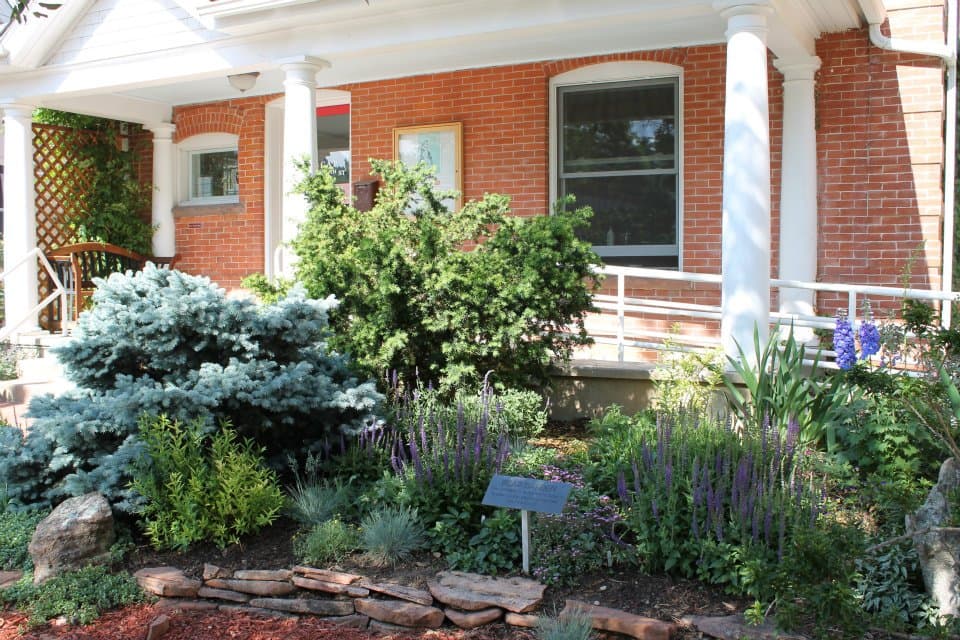 BCAP's red-brick office at 2118 14th Street, with a white-columned porch and a flowering garden.